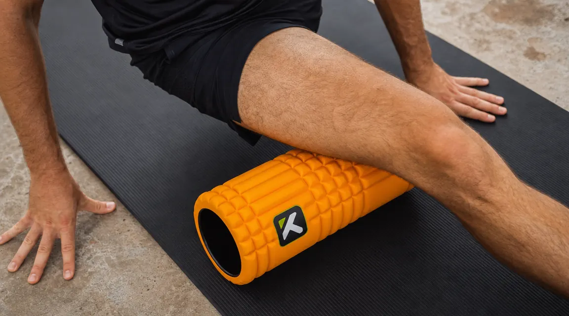 Close-up of hands placing a TriggerPoint GRID foam roller under a quad for rolling